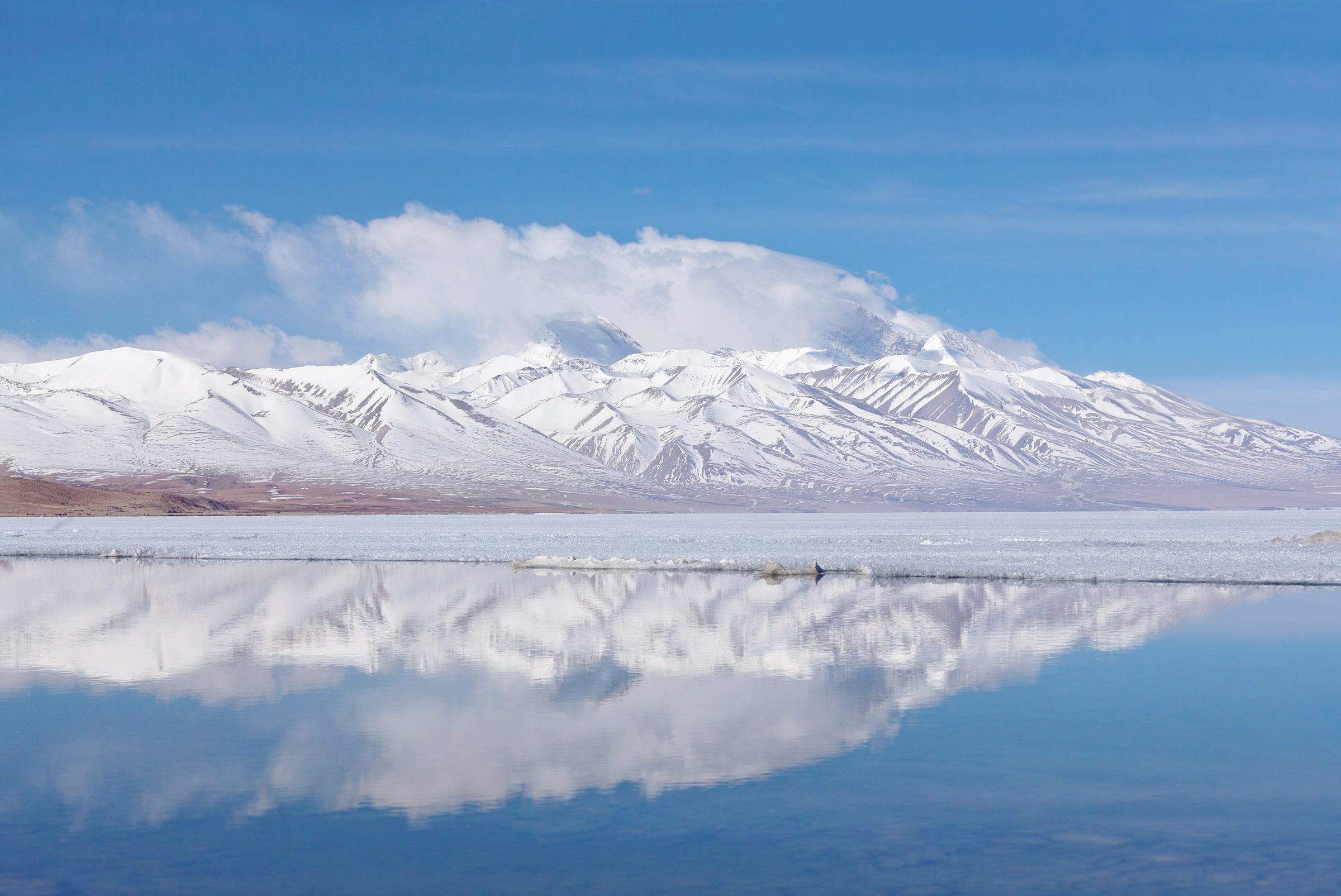 A still mountain lake reflecting snow-covered peaks.